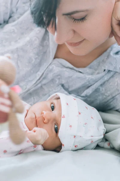 Moeder spelen met haar pasgeboren baby een teddy bear speelgoed — Stockfoto