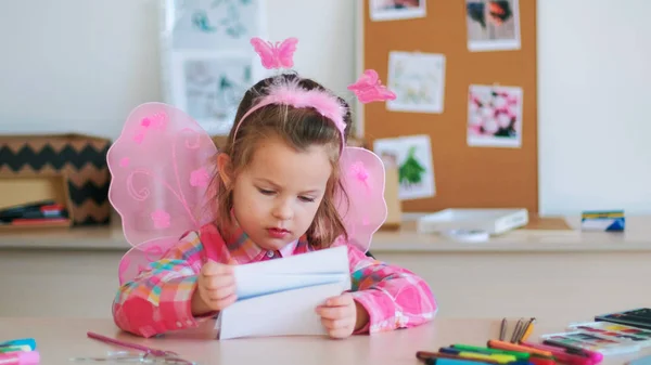 Linda niña mira imágenes en la lección de arte —  Fotos de Stock