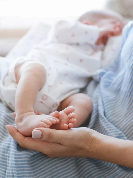 Mother holds the legs newborn baby — Stock Photo, Image