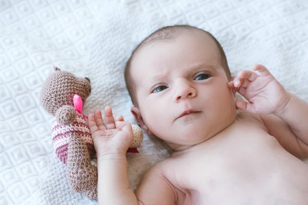 Bebê recém-nascido deitado na cama com seu próprio urso de brinquedo — Fotografia de Stock