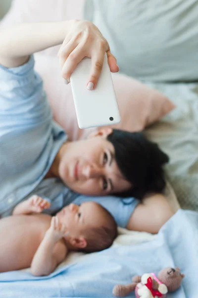 Madre toma una selfie en el teléfono inteligente con su hijo — Foto de Stock