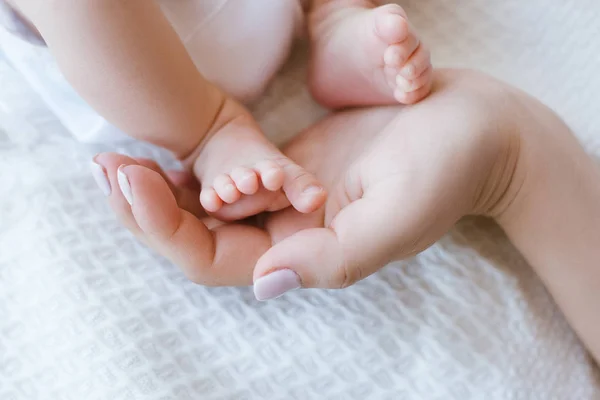 Moeder houdt benen pasgeboren baby — Stockfoto