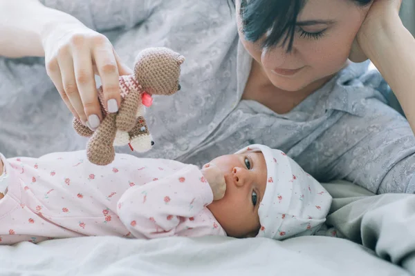 Moeder spelen met haar pasgeboren baby een teddy bear speelgoed — Stockfoto