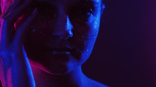 Brokat skóra kobieta dotykając twarz neon niebieskie światło — Wideo stockowe