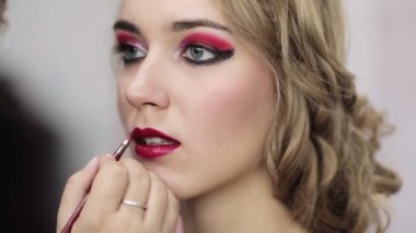 fashion makeup artist applying burgundy lip gloss