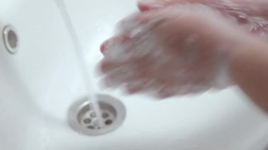 Coronavirus salgını olan kadın ellerini sabun köpüğü ile yıkıyor.