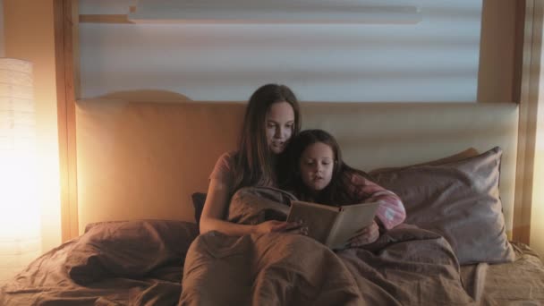 Libro de la hora de acostarse madre leyendo cama hija pequeña — Vídeos de Stock