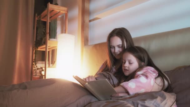 Madre hija ocio lectura libro cama noche — Vídeos de Stock