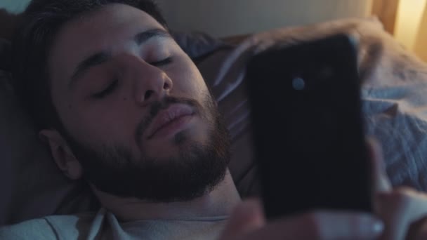 眠れない夜の退屈男はスマートフォンのベッドを使って — ストック動画