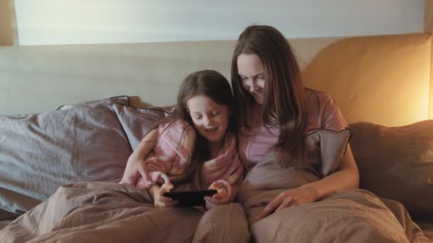 Familj hem fritid mamma dotter roligt telefon säng — Stockvideo