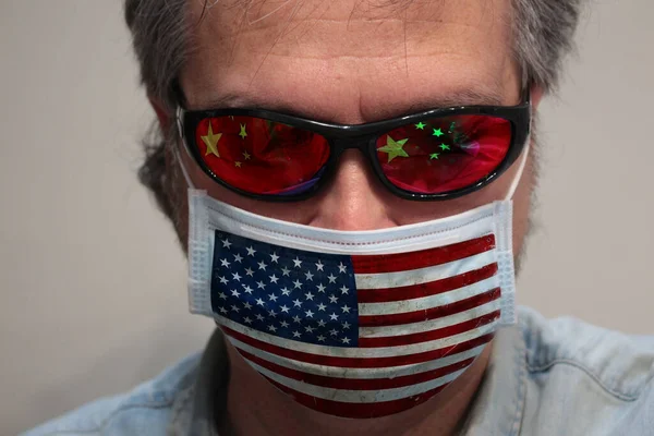 US versus China : An American portrait during Corona virus restrictions, wearing an US flag mask, but facing China flag.
