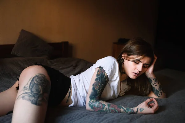 Молодая татуированная женщина лежит в постели — стоковое фото