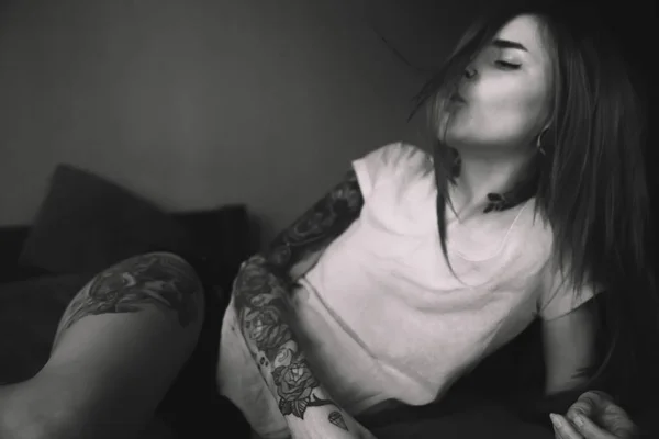 Joven mujer tatuada con el pelo largo acostado en la cama, jugando con — Foto de Stock