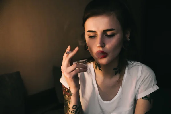 Курящая молодая татуированная женщина — стоковое фото