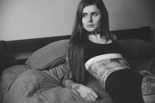 Junge tätowierte Frau mit langen Haaren liegt auf dem Bett. — Stockfoto