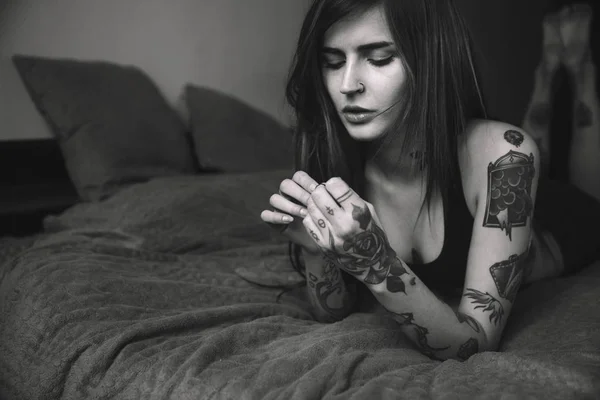 Jovem mulher tatuada com cabelos longos deitada na cama — Fotografia de Stock