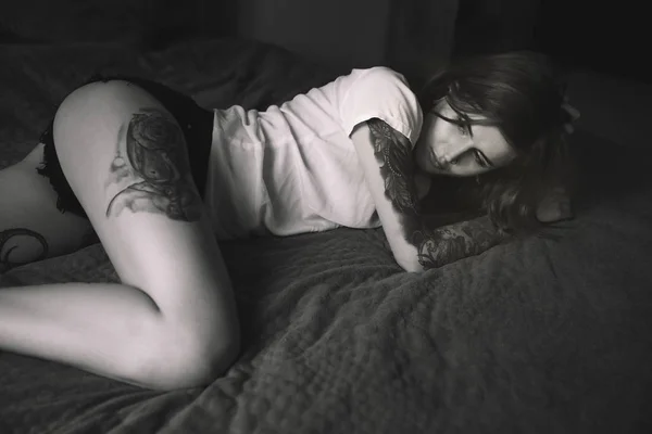 Молодая татуированная женщина лежит в постели Лицензионные Стоковые Фото