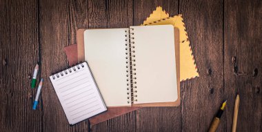 bir defter, zarf ve diğer ileti örneği ile ahşap bir masa. 