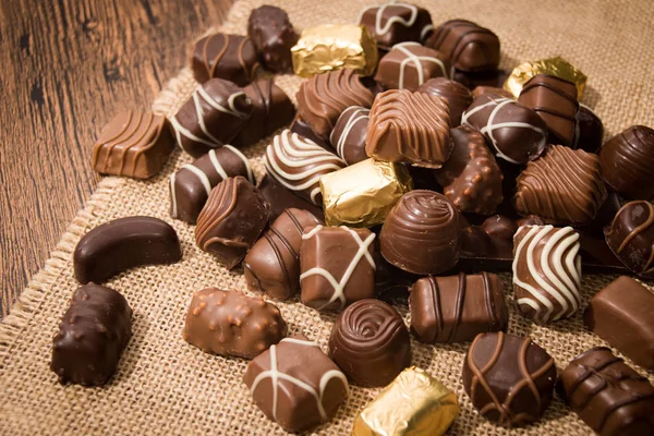 Chocolates variados em fundo de madeira — Fotografia de Stock
