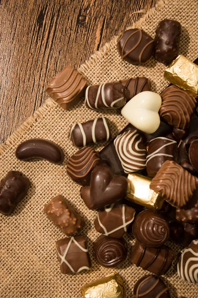 Chocolates surtidos sobre fondo de madera — Foto de Stock
