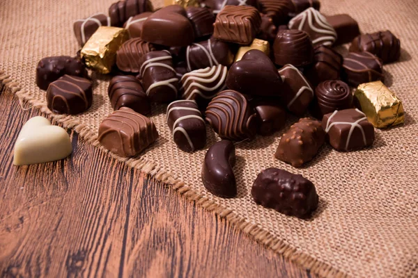 Chocolates variados em fundo de madeira — Fotografia de Stock