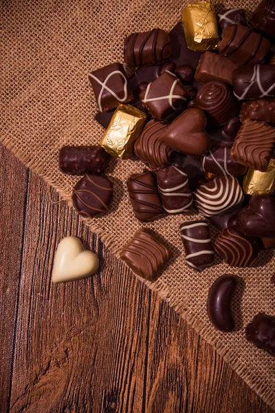 Chocolates variados em fundo de madeira — Fotografia de Stock