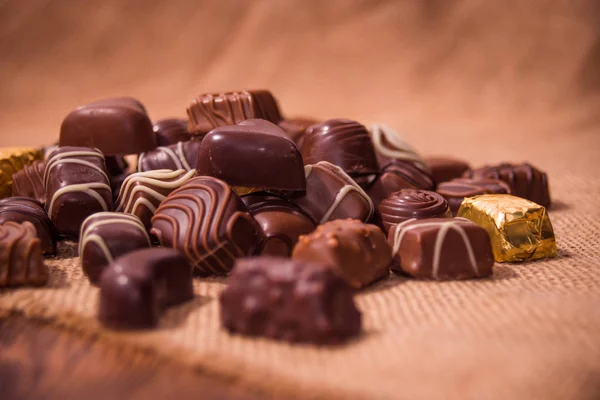 Chocolates surtidos sobre fondo de madera — Foto de Stock