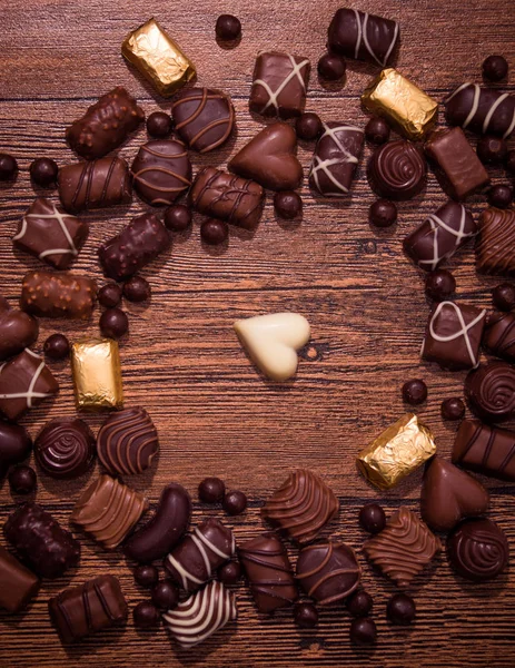 Chocolates surtidos sobre fondo de madera — Foto de Stock