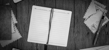 Defter ile zarf ahşap bir masa. Siyah ve beyaz. Üstten Görünüm