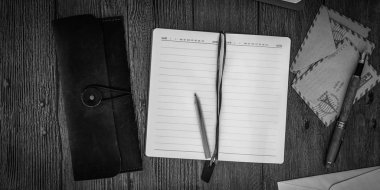 Defter ile zarf ahşap bir masa. Siyah ve beyaz. Üstten Görünüm