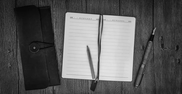 Cuaderno con sobre una mesa de madera. Blanco y negro. Vista superior —  Fotos de Stock