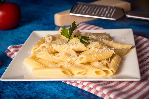 Penne makarna ile mavi bir arka plan üzerine parmesan peyniri