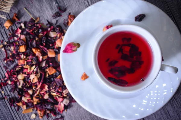Cup of tea mix of leaves, fruits and dried fruits on rustic back