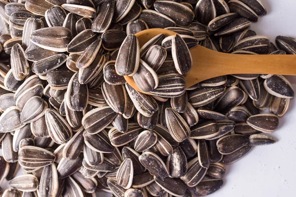 Sunflower seeds and a wooden spoon on a white background — Stock Photo, Image
