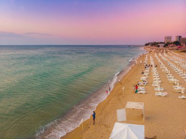 Kumlu plajda hava manzarası. Şemsiyeler, kum ve deniz dalgaları