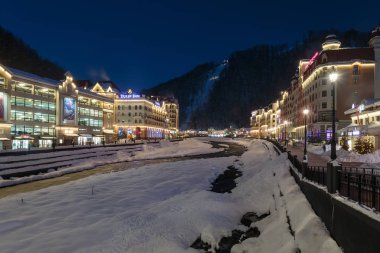 Rusya, Soçi, Krasnaya Polyana. Rosa Khutor, oteller ve mağazalar kış geceleri Mzımta nehirde beldesi. 23 Aralık 2016.