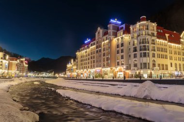 Rusya, Soçi, Krasnaya Polyana. Rosa Khutor, oteller ve mağazalar kış geceleri Mzımta nehirde beldesi. 23 Aralık 2016.