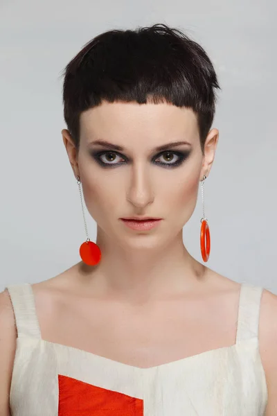 Bella giovane donna con i capelli corti neri e orecchini rossi. Taglio di capelli corto e stile, trucco naturale . — Foto Stock
