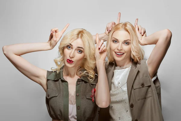 Twee mooie blonde modellen gezichten en laten hoorns. — Stockfoto