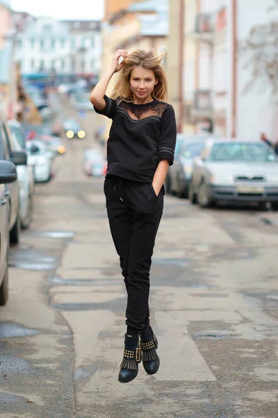 Street style - jolie fille en sweat-shirt sportif, pantalon et bottes lourdes rugueuses sautant sur la rue — Photo