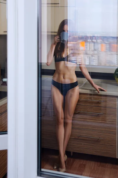 Portrait par la fenêtre. Fille attrayante en lingerie buvette — Photo