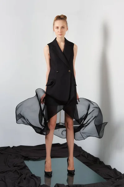 Fashion model in designers black sleeveless jacket and flying transparent skirt — Stock Photo, Image