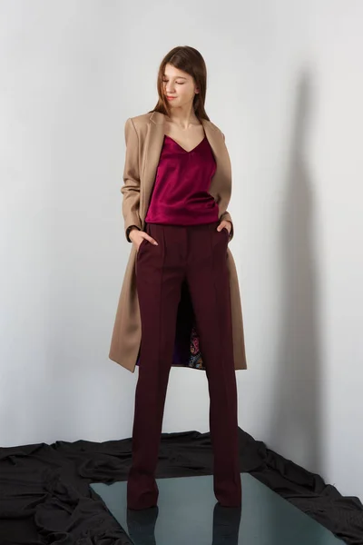 Приваблива модель моди в штанях, блузка на ремінцях і легке пальто руками в кишенях . — стокове фото