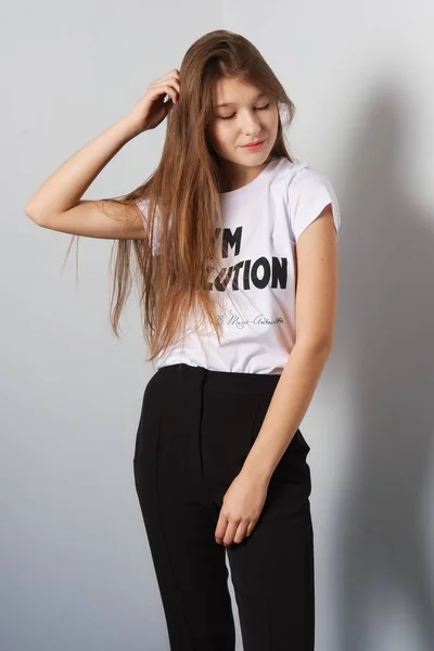 Atractiva modelo de moda en pantalones y camiseta con estampado tocando su pelo — Foto de Stock