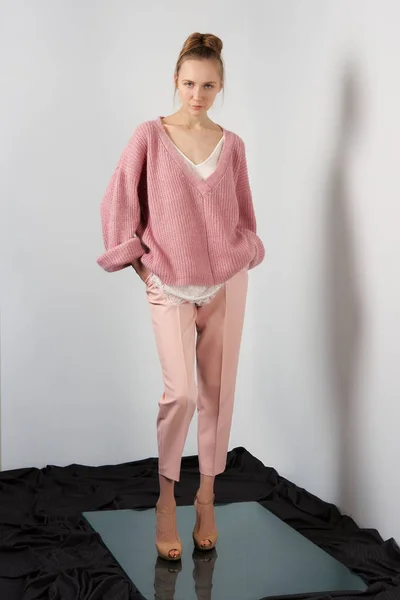 Красива дівчина в тонкому ангорському светрі і тонкі штани позують біля стіни — стокове фото