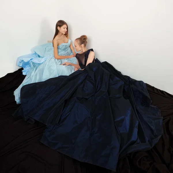 Dos modelos de moda en vestido revoloteando en el suelo. Dobladillo que fluye . — Foto de Stock