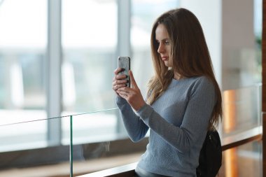 Balkonda fotoğraf onun smartphone ile pencereden yapım sırt çantası ile güzel kadın 