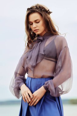Bulutlu bir günde kuma sakin yalnız moda modeli. Romantik, yumuşak, mistik, dalgın bir kız mavi etek ve şeffaf bluz görüntüsünü.