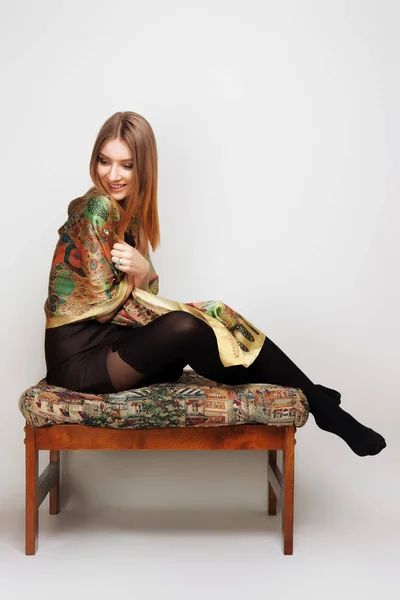 Bella ragazza in abito corto e sciarpa di seta colorata seduta su ch — Foto Stock