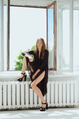 Pencere kenarında oturan çıplak vücut üzerinde elbise içinde şirin kız